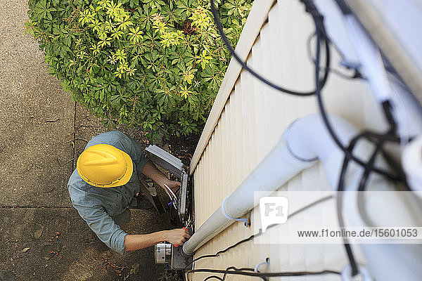 Elevated view of cable installer working on house access point