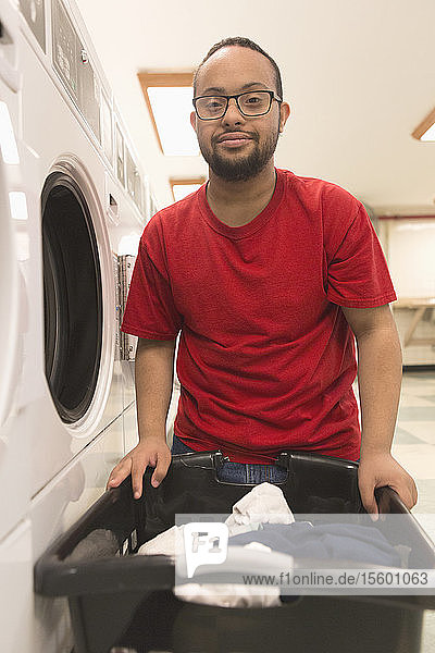 Afroamerikanischer Mann mit Down-Syndrom beim Wäschewaschen im Hauswirtschaftsraum
