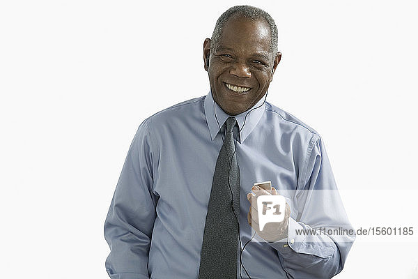 Porträt eines Geschäftsmannes  der einen iPod hört und lächelt