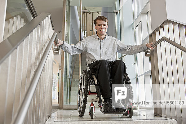 Geschäftsmann mit Querschnittslähmung in einem Rollstuhl am oberen Ende einer Treppe