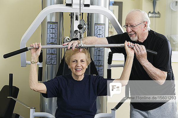 Älteres Paar bei der Arbeit an einem Trainingsgerät in einem Fitnessstudio