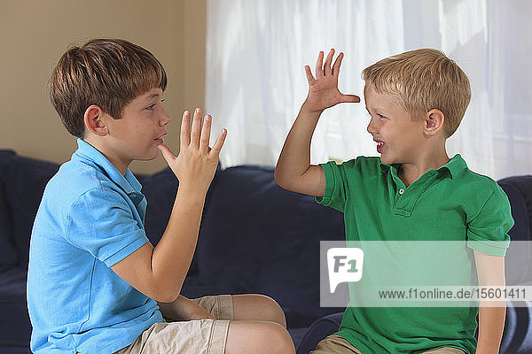 Jungen mit einer Hörbehinderung  die auf ihrer Couch in amerikanischer Gebärdensprache Mama  Papa oder Eltern gebärden