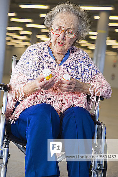 Blick auf eine ältere Frau im Rollstuhl mit Medikamenten in der Hand