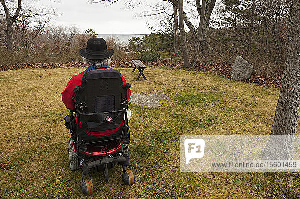 Mann mit Multipler Sklerose in einem motorisierten Rollstuhl in seinem Hinterhof