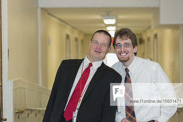 Portrait of man with Down Syndrome smiling with a collaborator in the State Capitol office corridor