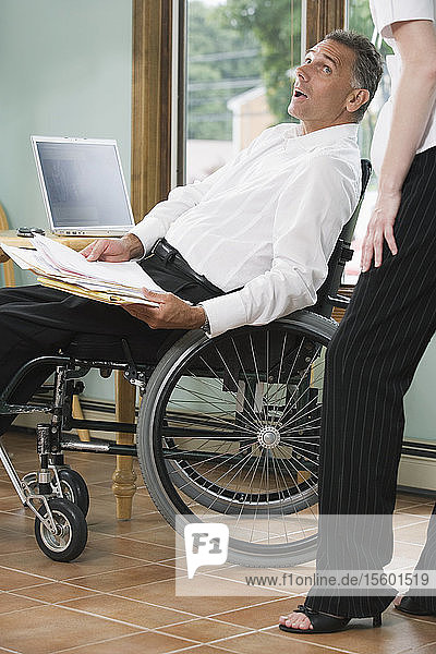Side profile of a mature man sitting in a wheelchair with a Spinal Cord Injury and holding a file