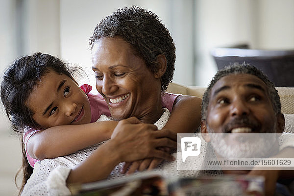 Ein lächelndes reifes Paar genießt die Zeit mit seiner Enkelin in seinem Haus