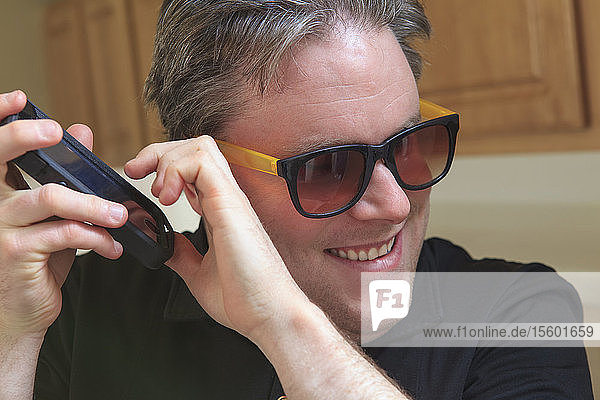 Ein Mann mit angeborener Blindheit nutzt eine Hörhilfe  um seine Textnachrichten zu hören