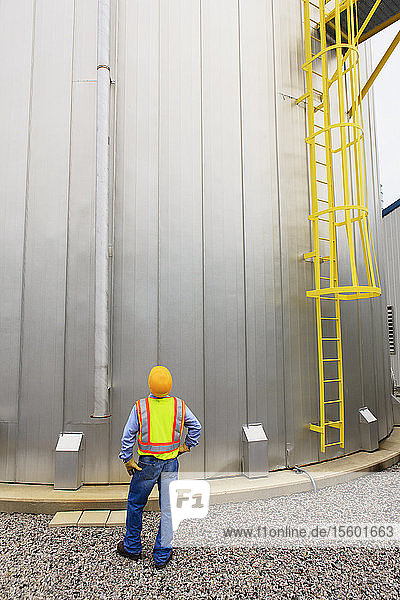 Engineer at electric power plant standing near water storage tank