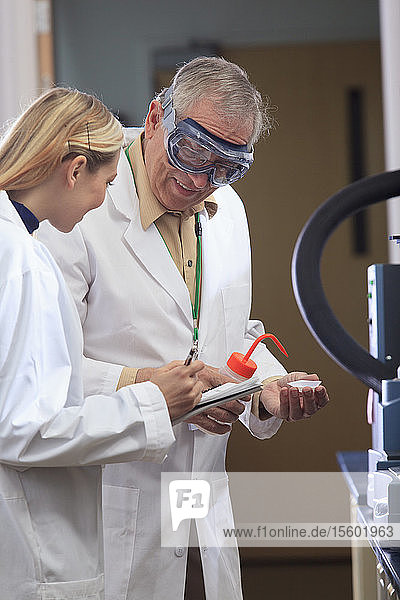 Professor working with engineering student adding ethanol to sample tray in a laboratory
