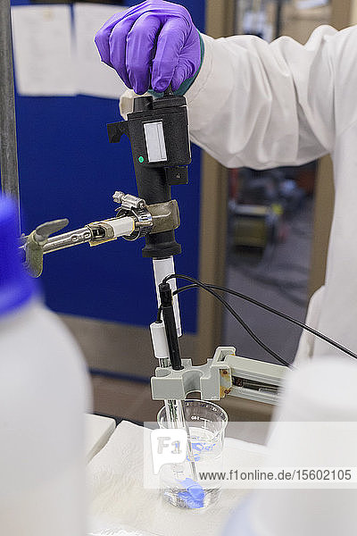 Labortechniker  der während der pH-Messung Reagenz zur Probe hinzufügt
