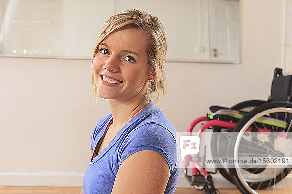 Junge Frau mit einer Rückenmarksverletzung im Rollstuhl in einem Yogastudio