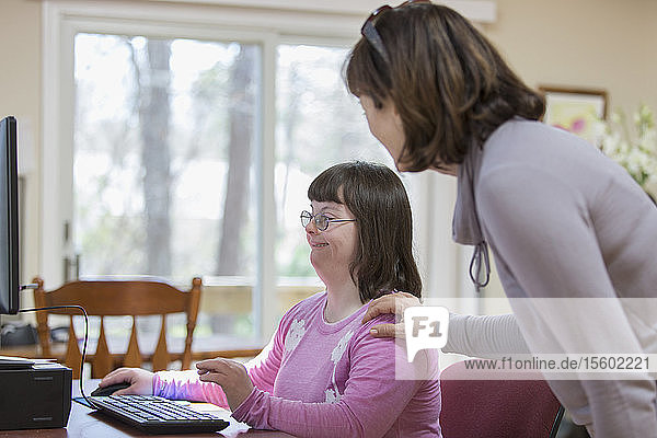 Mädchen mit Down-Syndrom und ihre Mutter am Computer