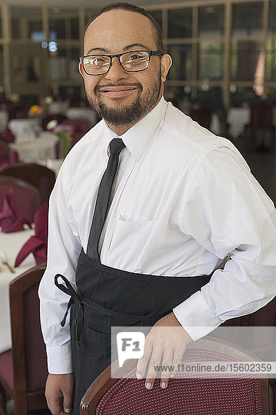 Porträt eines afroamerikanischen Mannes mit Down-Syndrom als Kellner in einem Restaurant