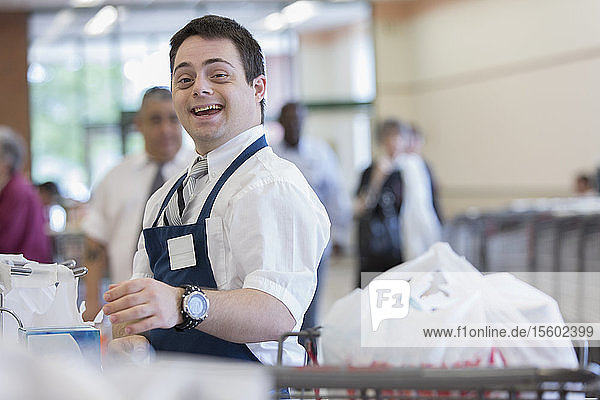 Glücklicher Mann mit Down-Syndrom bei der Arbeit in einem Lebensmittelladen
