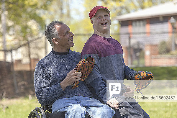 Happy father with Spinal Cord Injury and his son with Down Syndrome about to play baseball in park