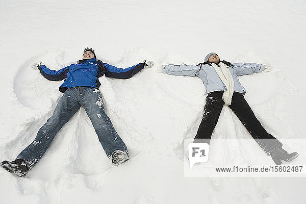 Junges Paar macht Schneeengel