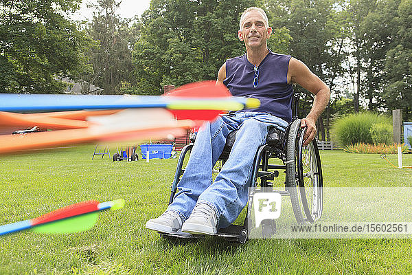 Man with spinal cord injury in wheelchair preparing for archery practice