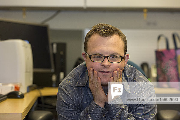 Portrait of hospital aid worker with Down Syndrome sitting at his desk
