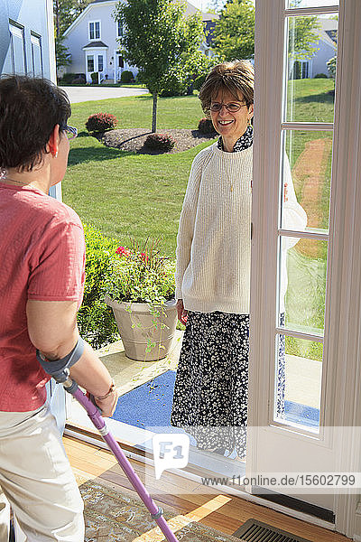 Frau mit zerebralen Lähmungen begrüßt jemanden an der Tür ihres Hauses