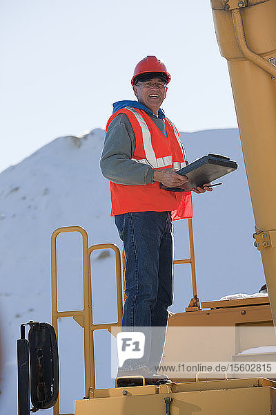 Engineer with electronic clipboard on an earth mover