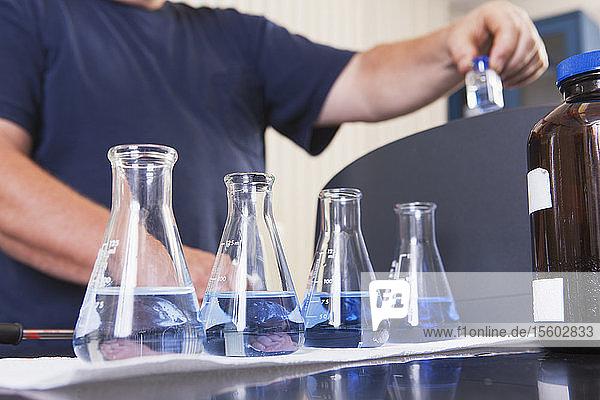 Ingenieur mit Probenflaschen mit Indigolösung und ozonisiertem Wasser und Fläschchen in der Hand zur Analyse in der Wasseraufbereitungsanlage