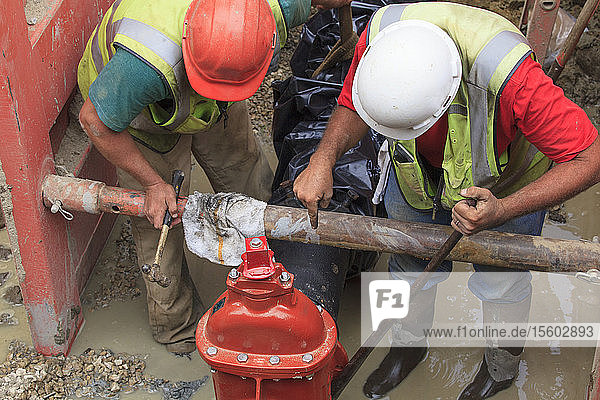 Bauarbeiter beim Einstellen der Schieberstellung an der Wasserleitung