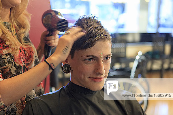 Trendy man with a spinal cord injury at a hair salon getting a hair cut