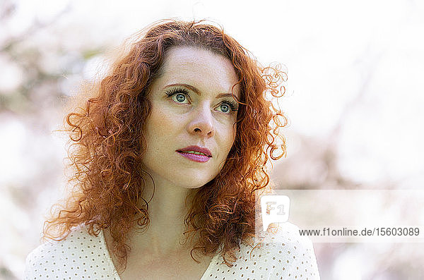 Portrait of a woman with red hair among the cherry blossoms; Vancouver  British Columbia  Canada