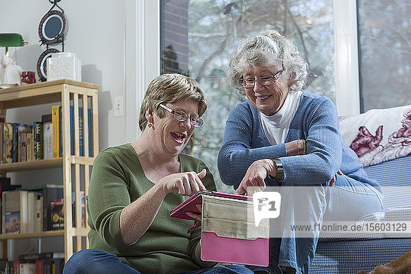 Frau mit Autismus benutzt mit ihrer Mutter ein digitales Tablet