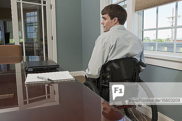 Businessman with spinal cord injury in a wheelchair in an office