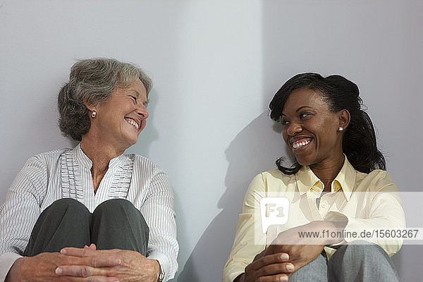 Zwei Frauen sitzen zusammen und lächeln