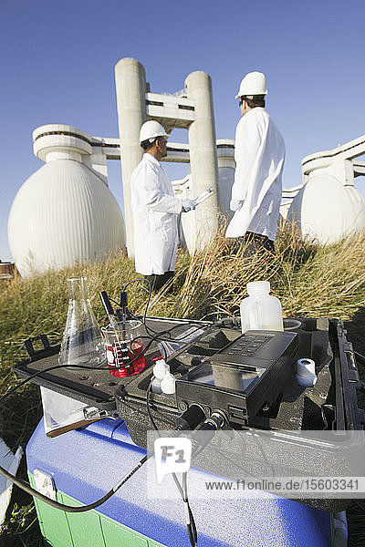 Wasserprobe und PH-Meter mit zwei Wissenschaftlern im Hintergrund