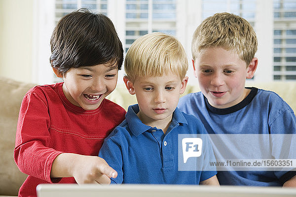 Blick auf drei Freunde  die auf einen Laptop schauen.