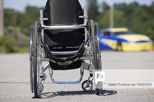 Rollstuhl und Rennwagen im Hintergrund