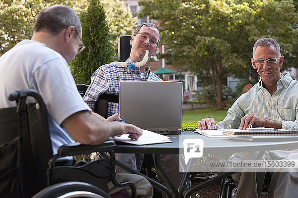 Three businessmen with disabilities at a cafÃƒÂ©