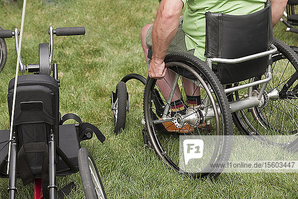 Mann sitzt im Rollstuhl in einem Park