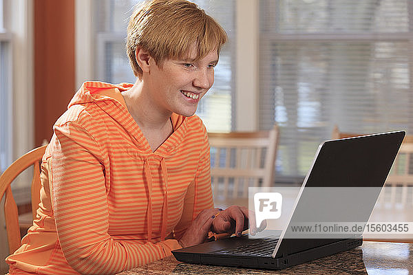 Junge Frau mit rechtsseitiger Cerebralparese benutzt ihren Laptop