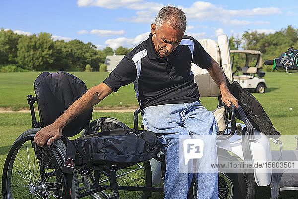 Ein Mann mit einer Rückenmarksverletzung in einem adaptiven Golfwagen steigt in seinen Rollstuhl