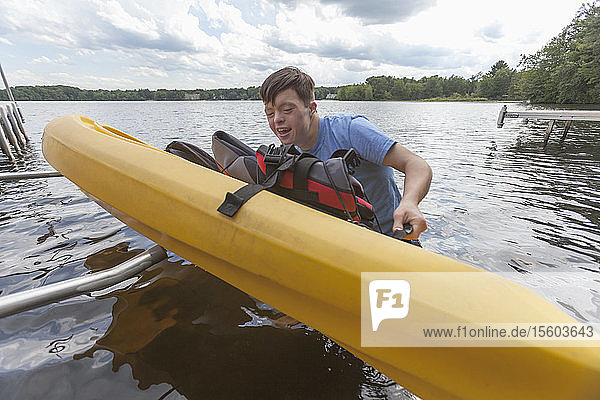 Young man with Down Syndrome preparing to use a kayak in a lake