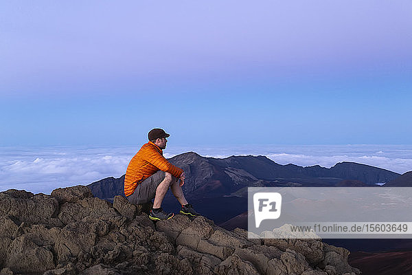 Tourist sits on a mountain summit looking out  Haleakala; Maui  Hawaii  United States of America