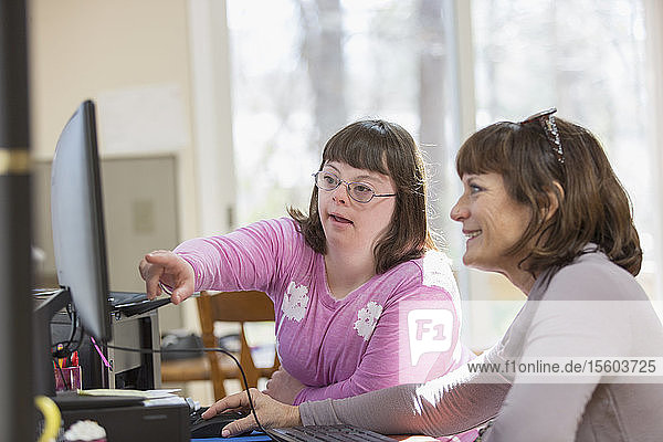 Mädchen mit Down-Syndrom und ihre Mutter am Computer