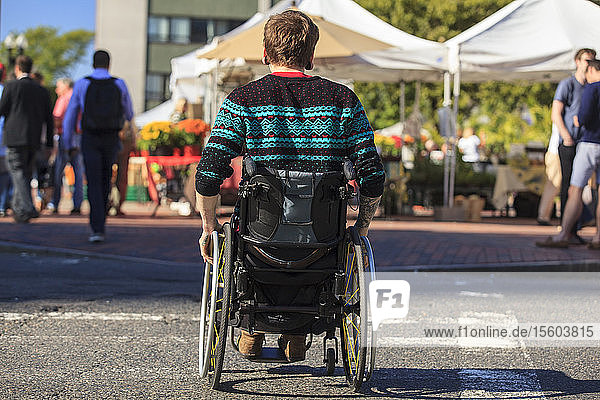 Trendiger Mann mit einer Rückenmarksverletzung im Rollstuhl auf einem Markt in der Stadt