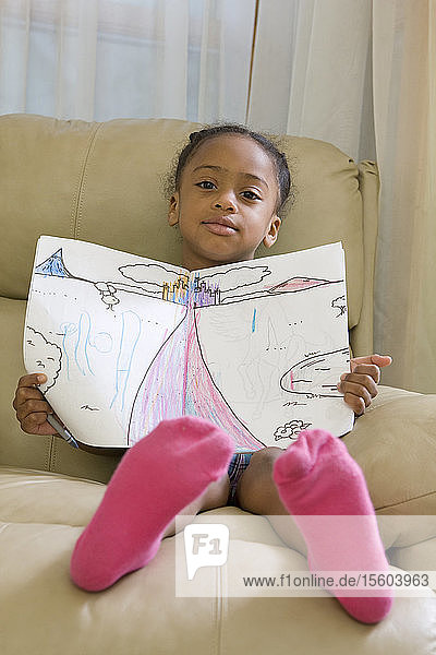 Hispanisches Mädchen sitzt und zeigt eine Zeichnung
