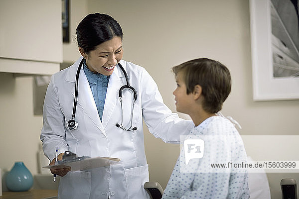 Lächelnde Ärztin im Gespräch mit einem jungen Patienten