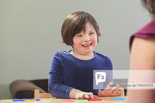 Little girl with Down Syndrome playing a learning game with her Mom