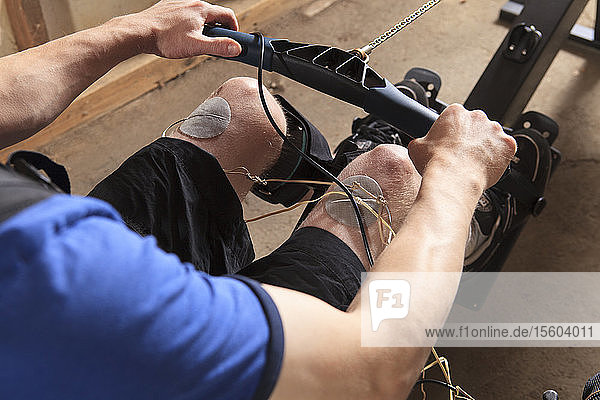 Ein Mann mit einer Rückenmarksverletzung benutzt sein Rudergerät  an dem ein Muskelstimulator angebracht ist