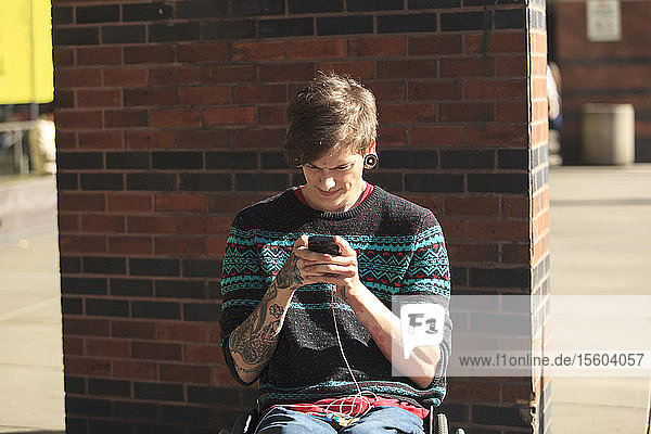 Trendy man with a spinal cord injury in wheelchair taking his text messages