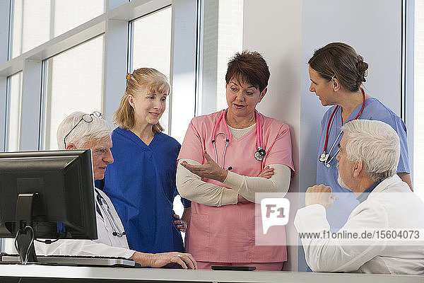Nurses and doctors discussing patients while at computer. Doctor has Muscular Dystrophy