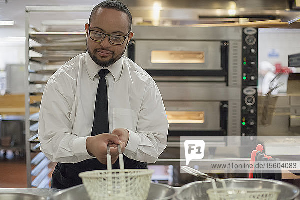 African American man with Down Syndrome as a chef cooking in commercial kitchen